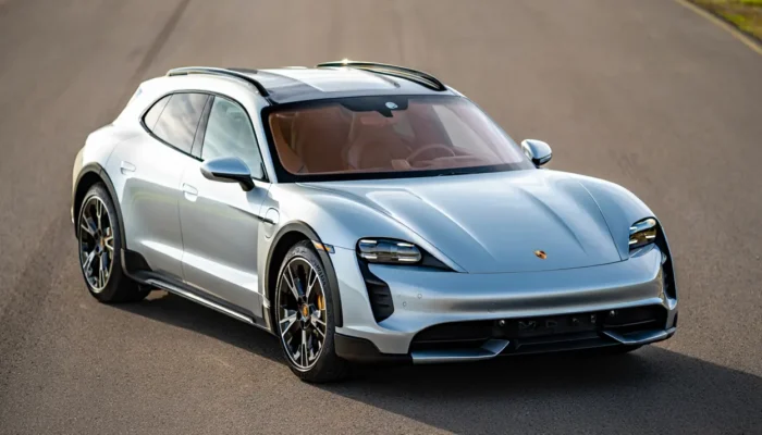 Silver Porsche Taycan Cross Turismo parked on an open road under daylight.