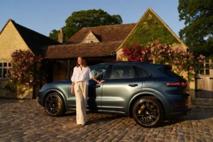 Person leaning on a car outside their house in the UK with sunshine