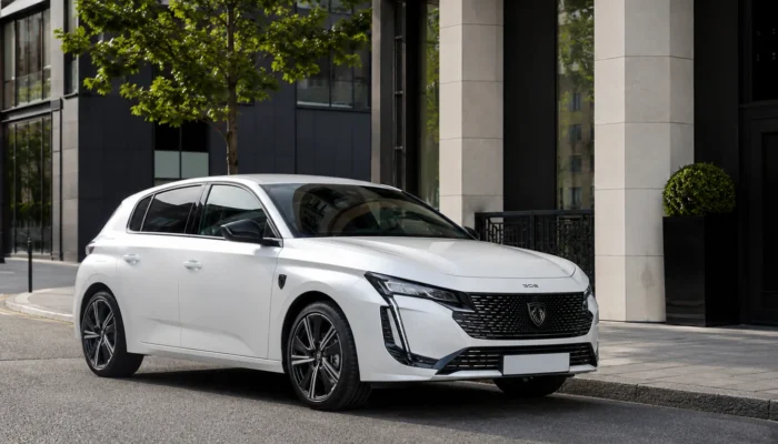 White Peugeot 308 parked on a city street beside modern buildings