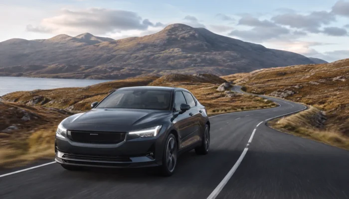 Black Polestar 2 driving on a mountain road beside a loch