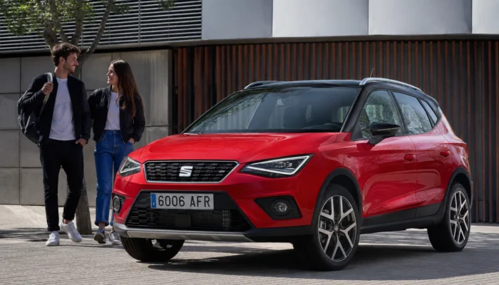 Red Seat Arona parked on a street as a couple walk past